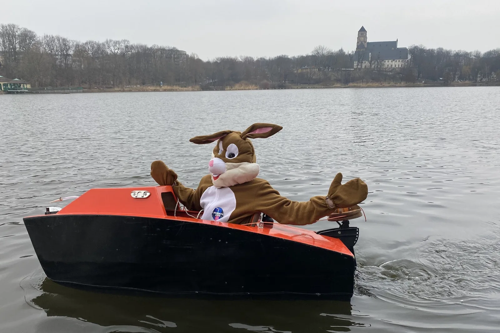 Der Osterhase der Aktion Chemnitz sucht das Osternest in einem Boot auf dem Schlossteich, im Hintergrund die Schlosskirche